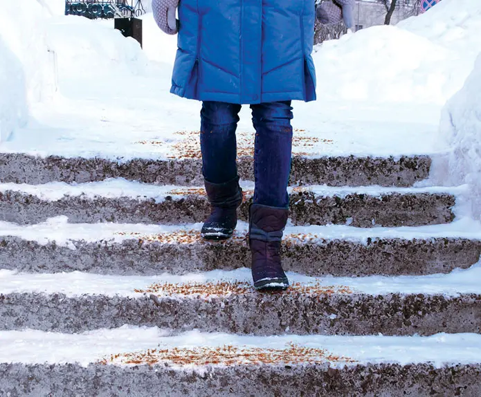 Person walking on winter steps where traction granules have been applied